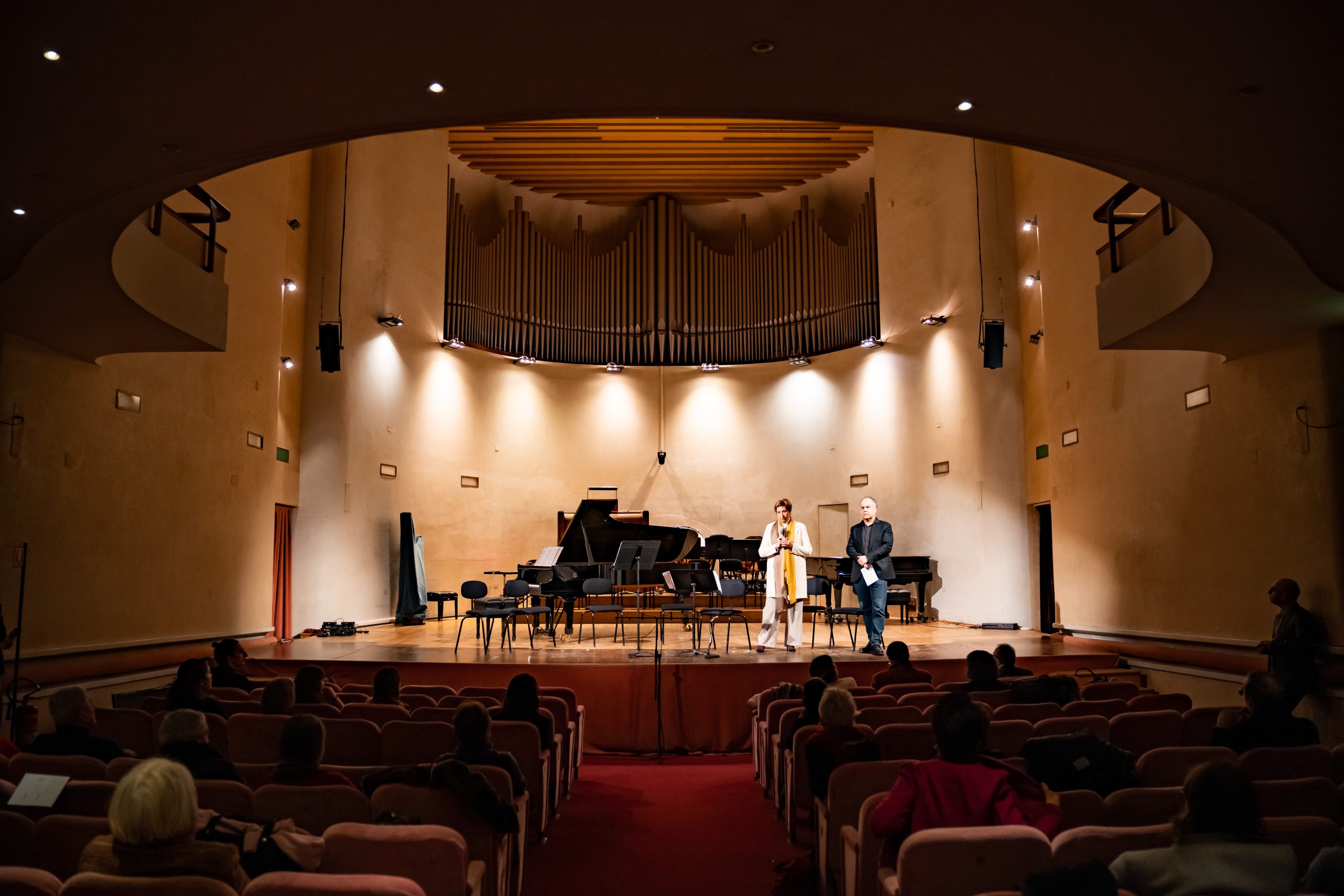 Due persone su un palco di un auditorium con strumenti musicali.