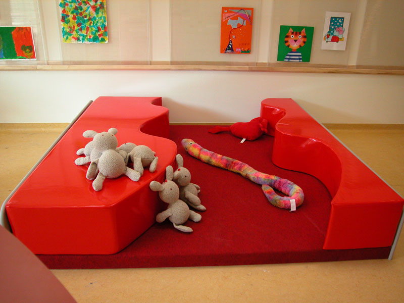 Area giochi per bambini con peluche e decorazioni colorate su pareti nella stanza.