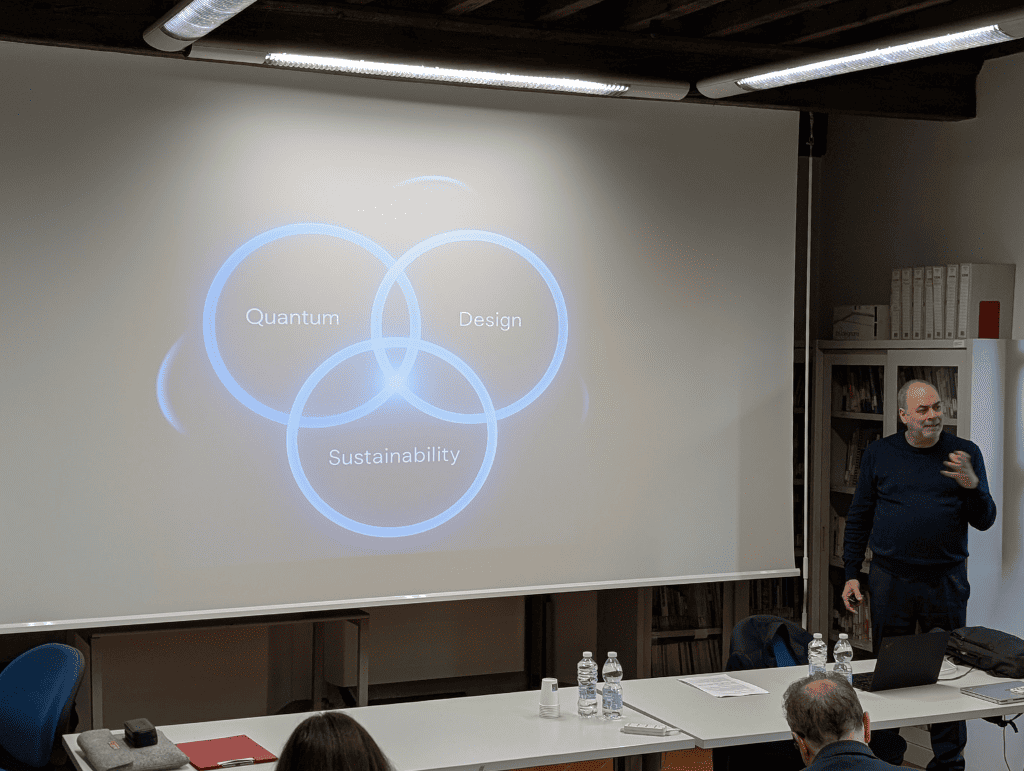 Relatore in una presentazione su Quantum, Design e Sostenibilità, con slide proiettata e pubblico attento.