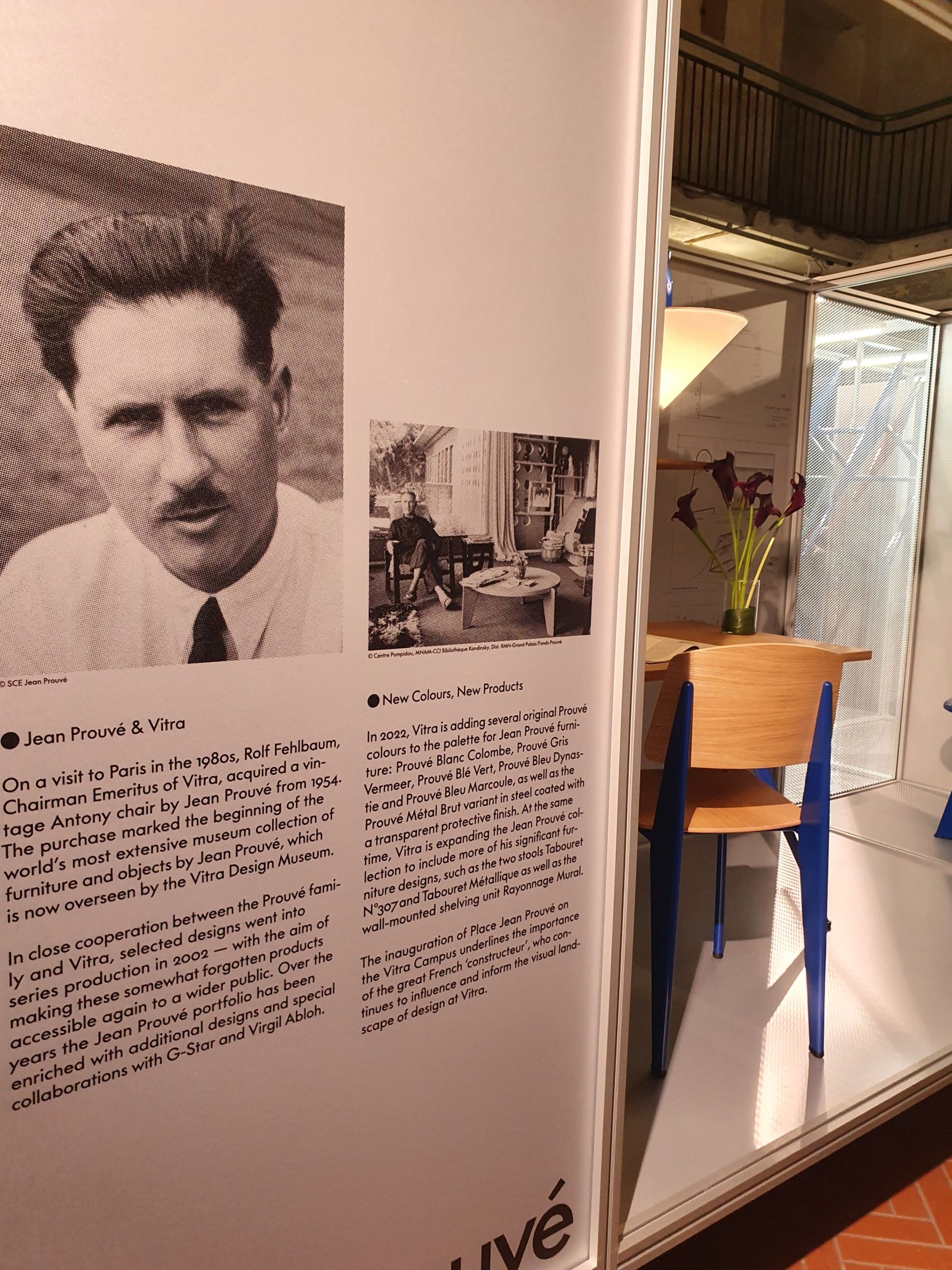 Esposizione su Jean Prouvé e Vitra con immagini storiche e testo descrittivo, arredamento di design moderno in vista.