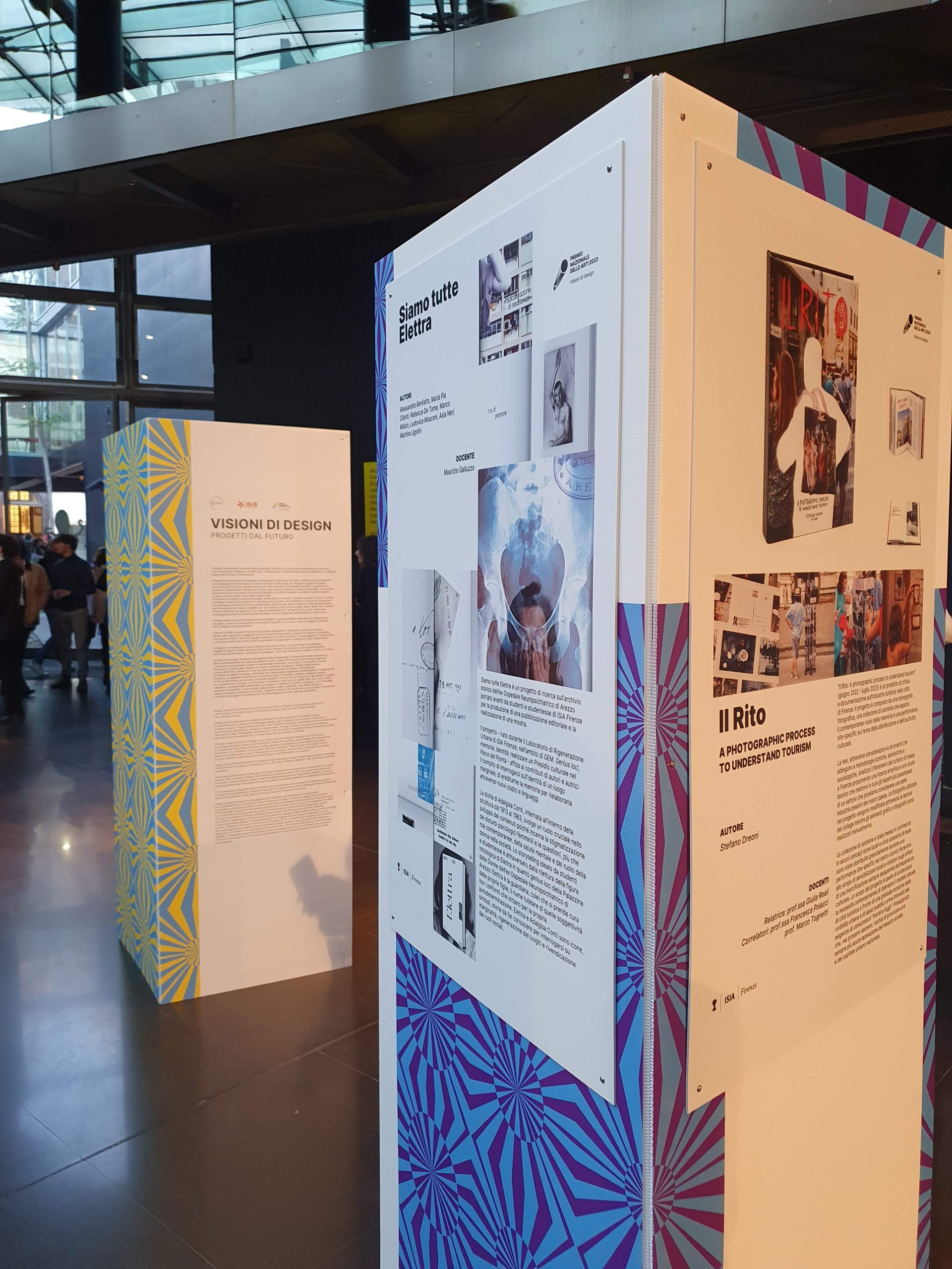 Esposizione di design con pannelli informativi e opere, in un contesto di luce naturale e architettura moderna.