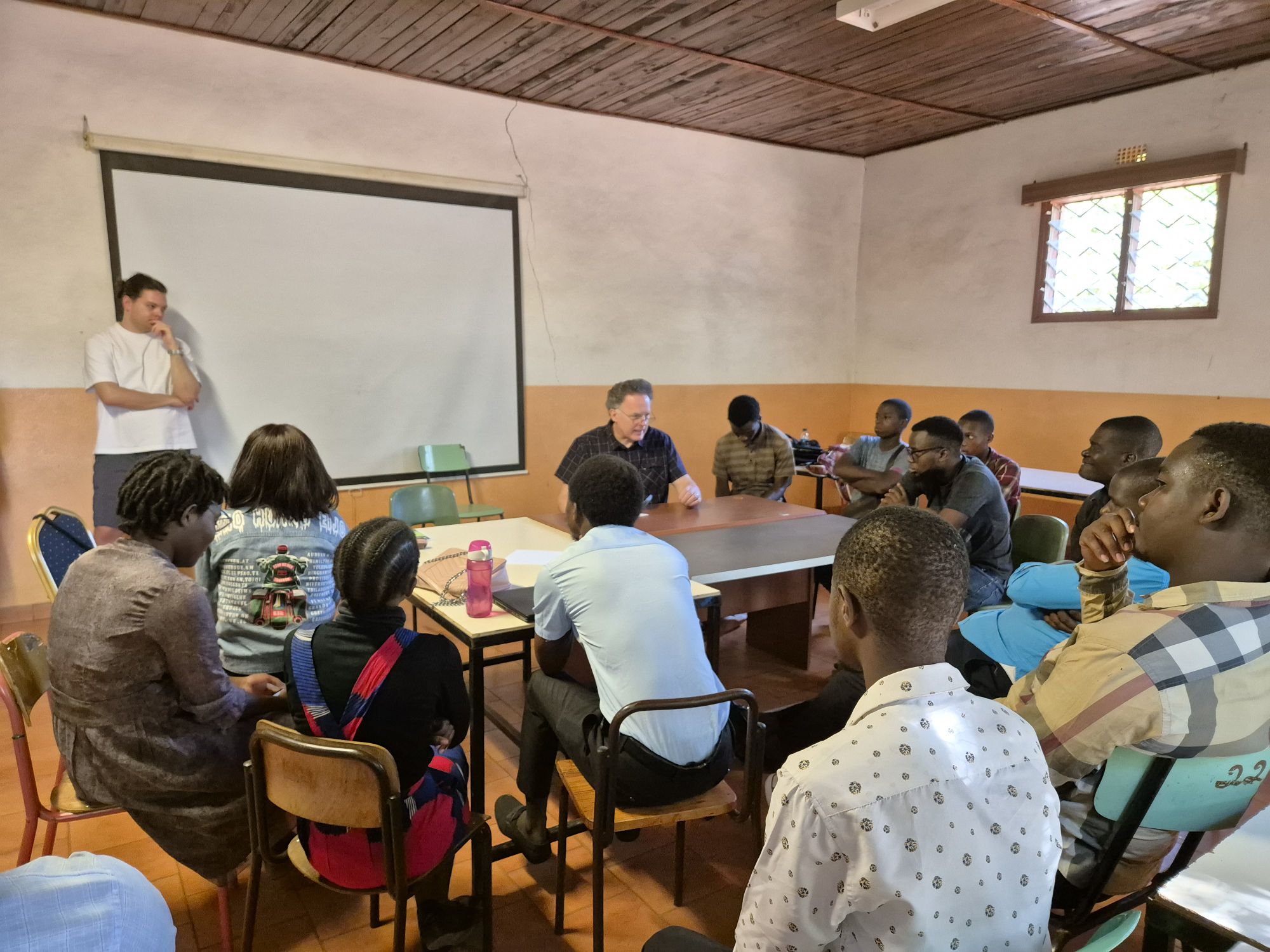 Gruppo di persone durante una presentazione in una sala conferenze con lavagna bianca e tavoli.