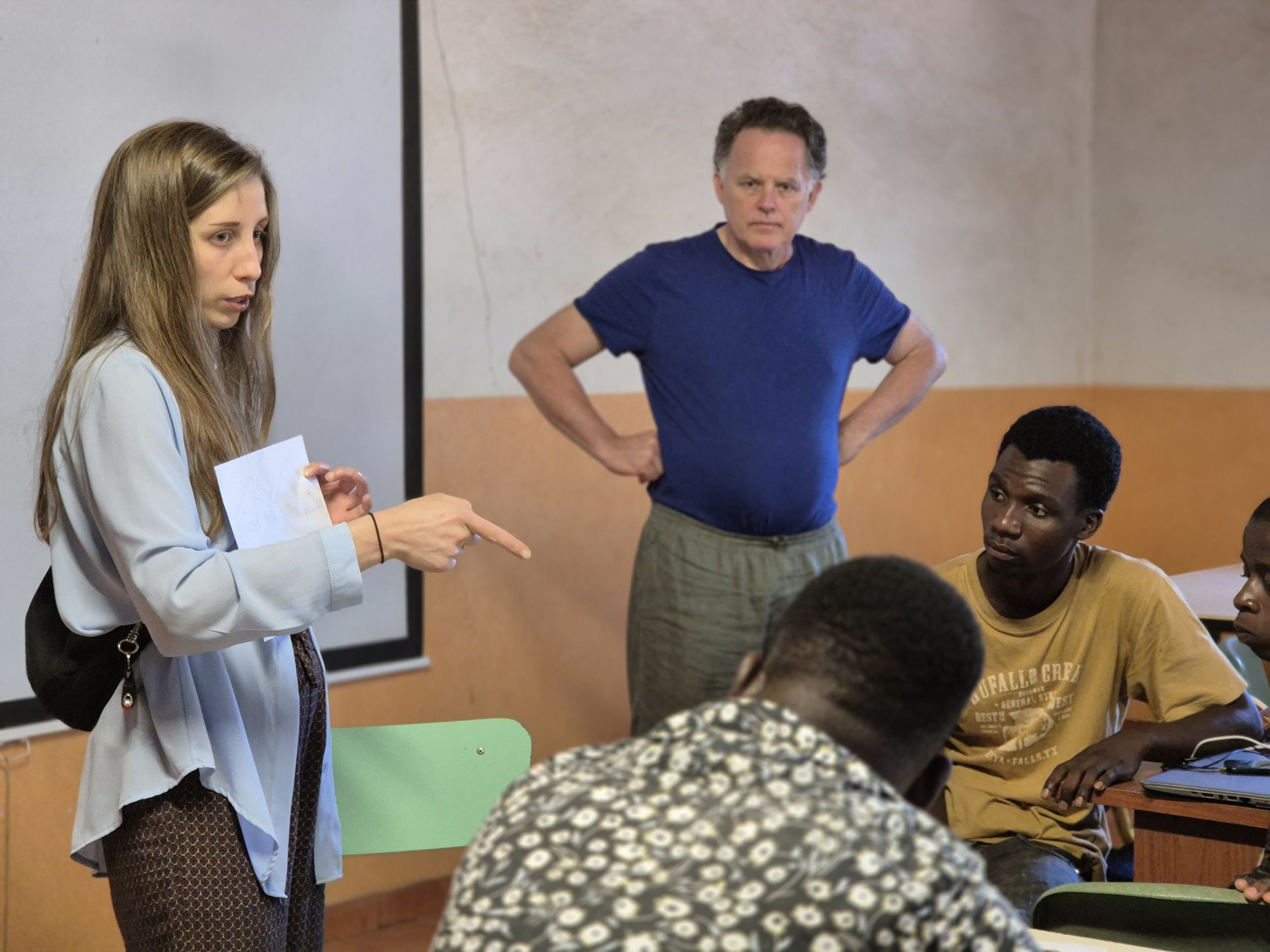 Insegnante discute con studenti in un'aula, evidenziando un ambiente educativo e partecipativo.