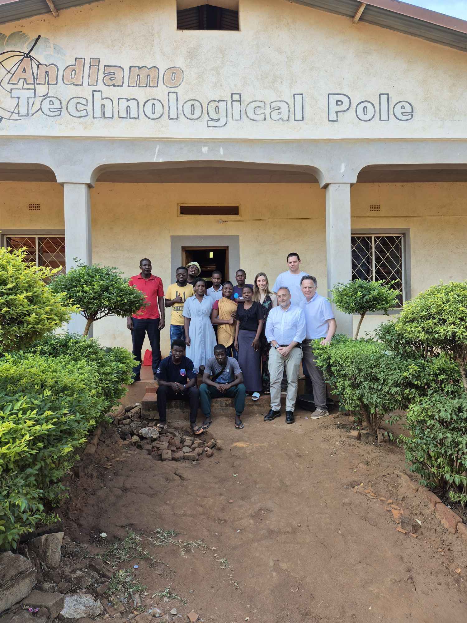 Gruppo di persone davanti all'edificio dell'Andiamo Technological Pole, circondato da piante verdi.