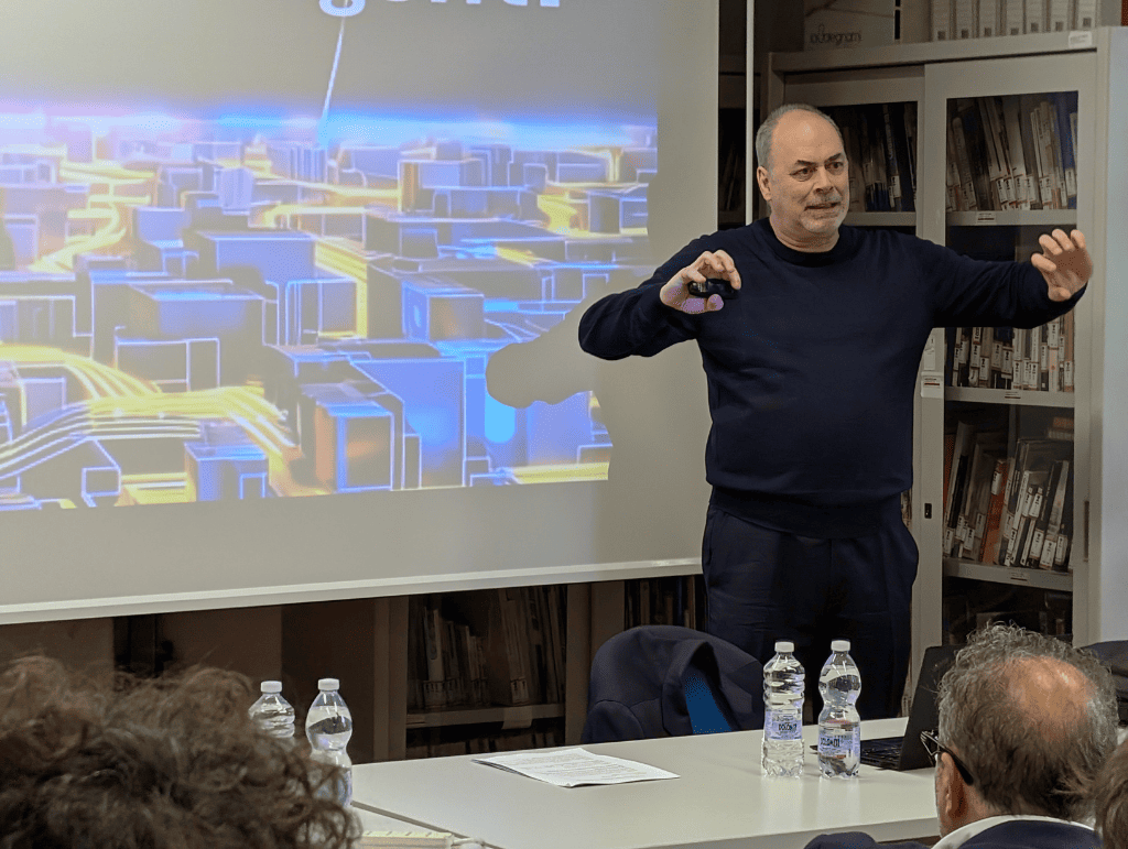 Persona presenta davanti a un proiettore, tema città futuristica; pubblico attento, atmosfera ufficio.