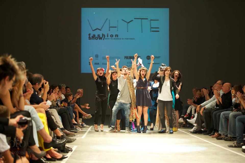 Sfilata di moda in passerella, applausi del pubblico, gruppo di stilisti e modelli festeggia sotto il logo di Whyte.