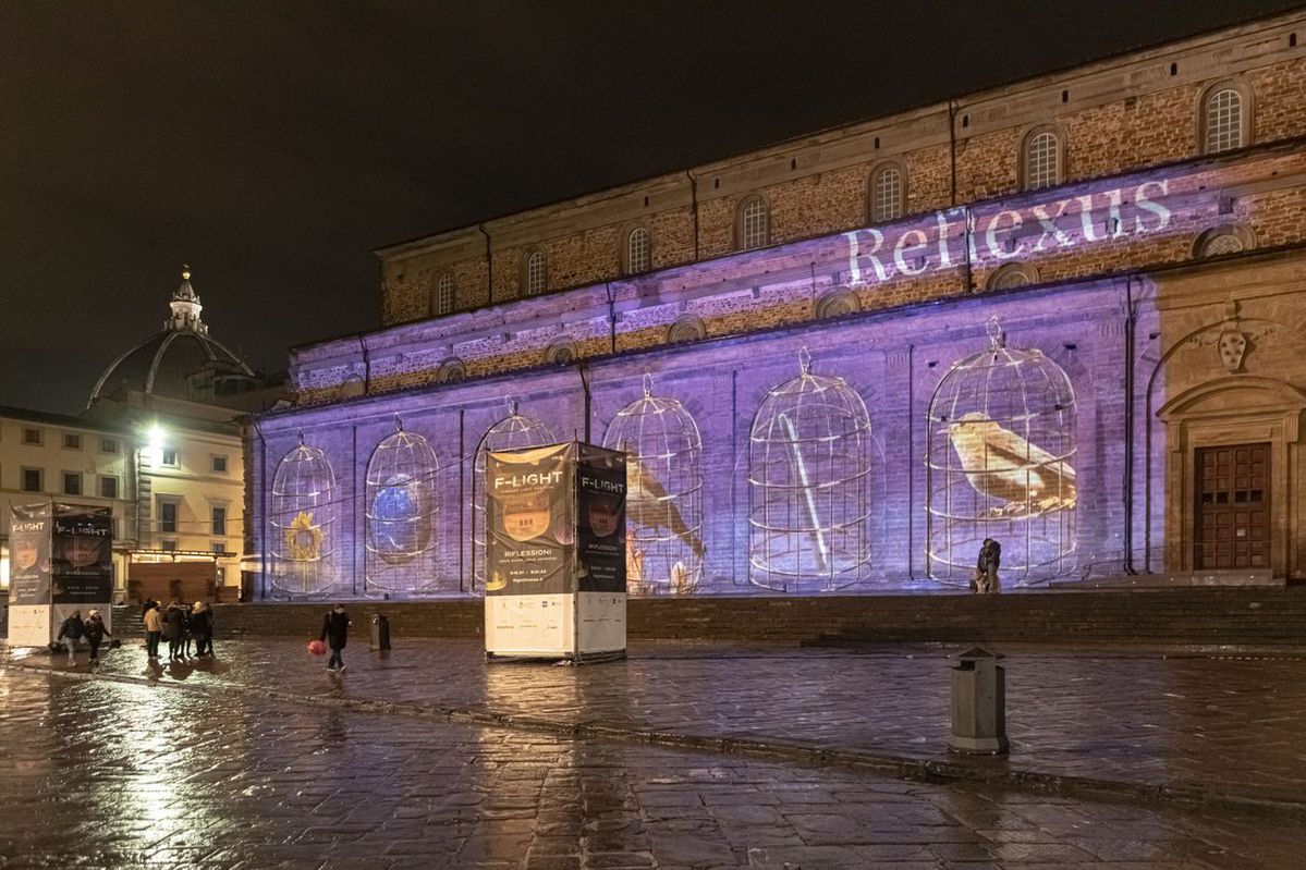 Facciata di chiesa illuminata con proiezioni artistiche notturne durante il festival F-Light a Firenze.