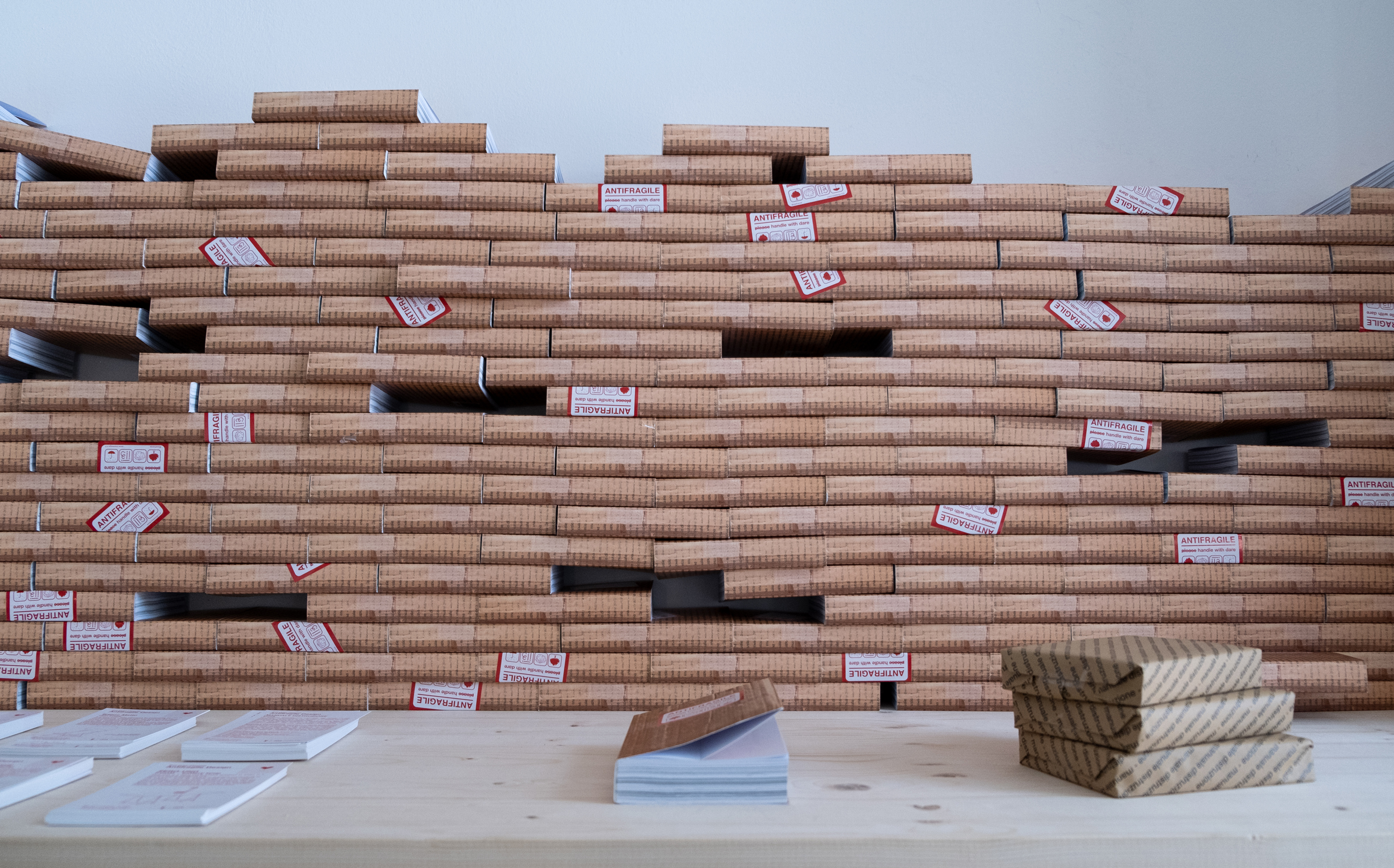 Pile di scatole di cartone etichettate Antifragile su un tavolo di legno.