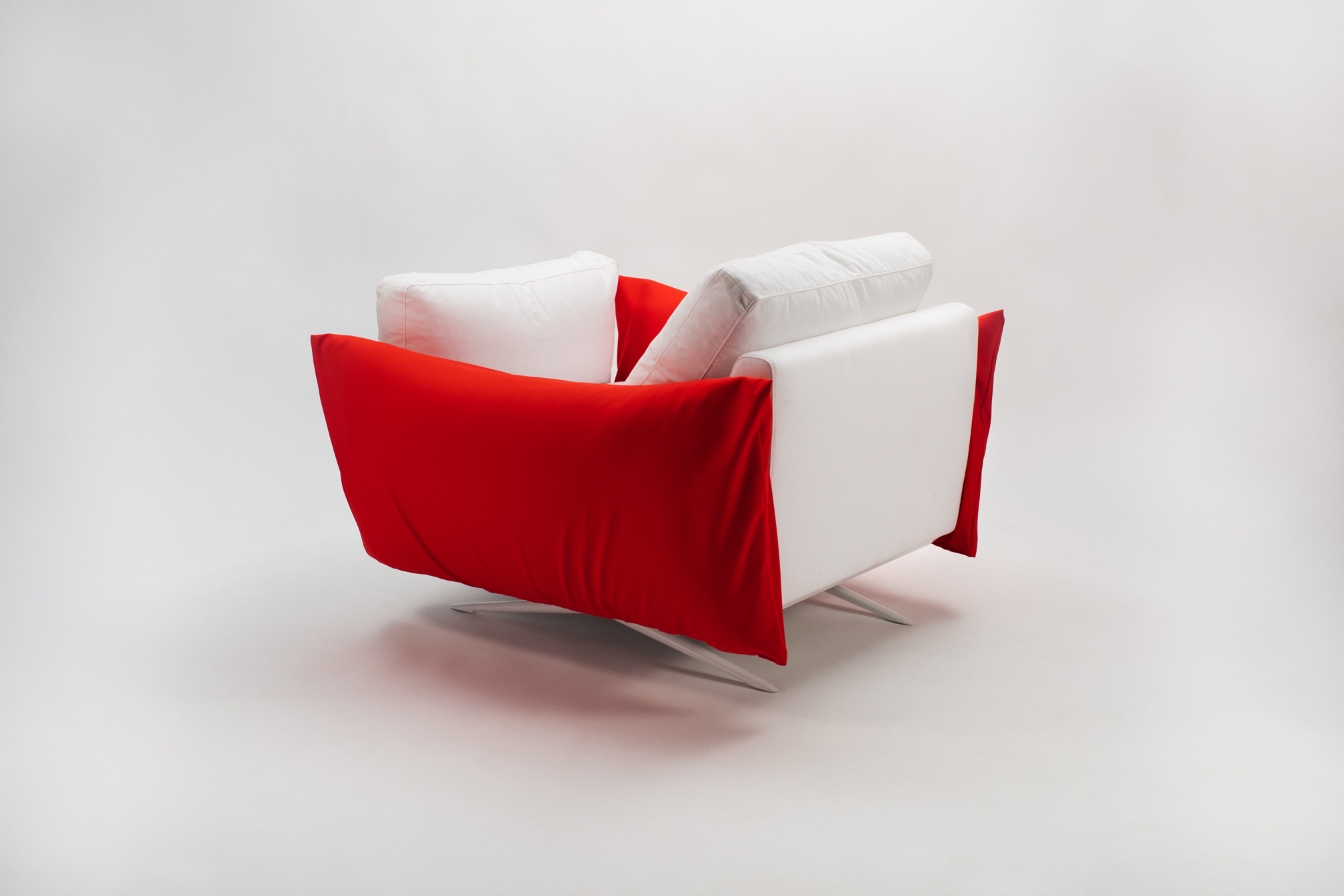 Poltrona moderna bianca e rossa su sfondo chiaro, design elegante e minimalista.