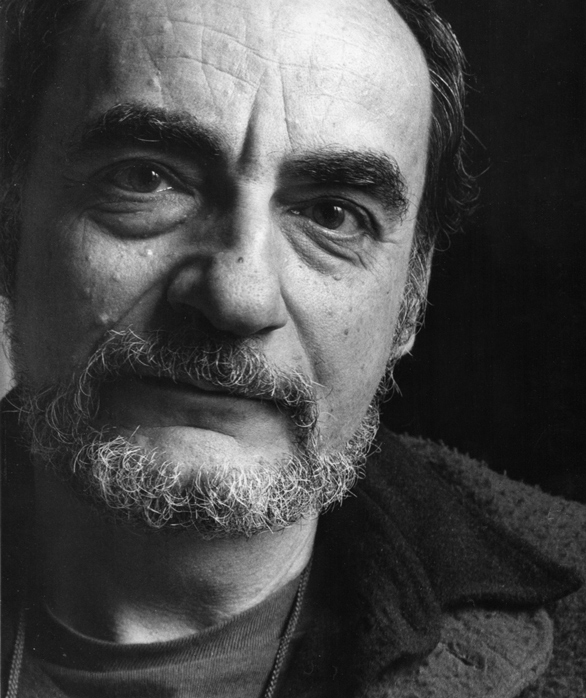 Ritratto in bianco e nero di un uomo con barba, occhi espressivi e sguardo intenso, indossando abiti casual.