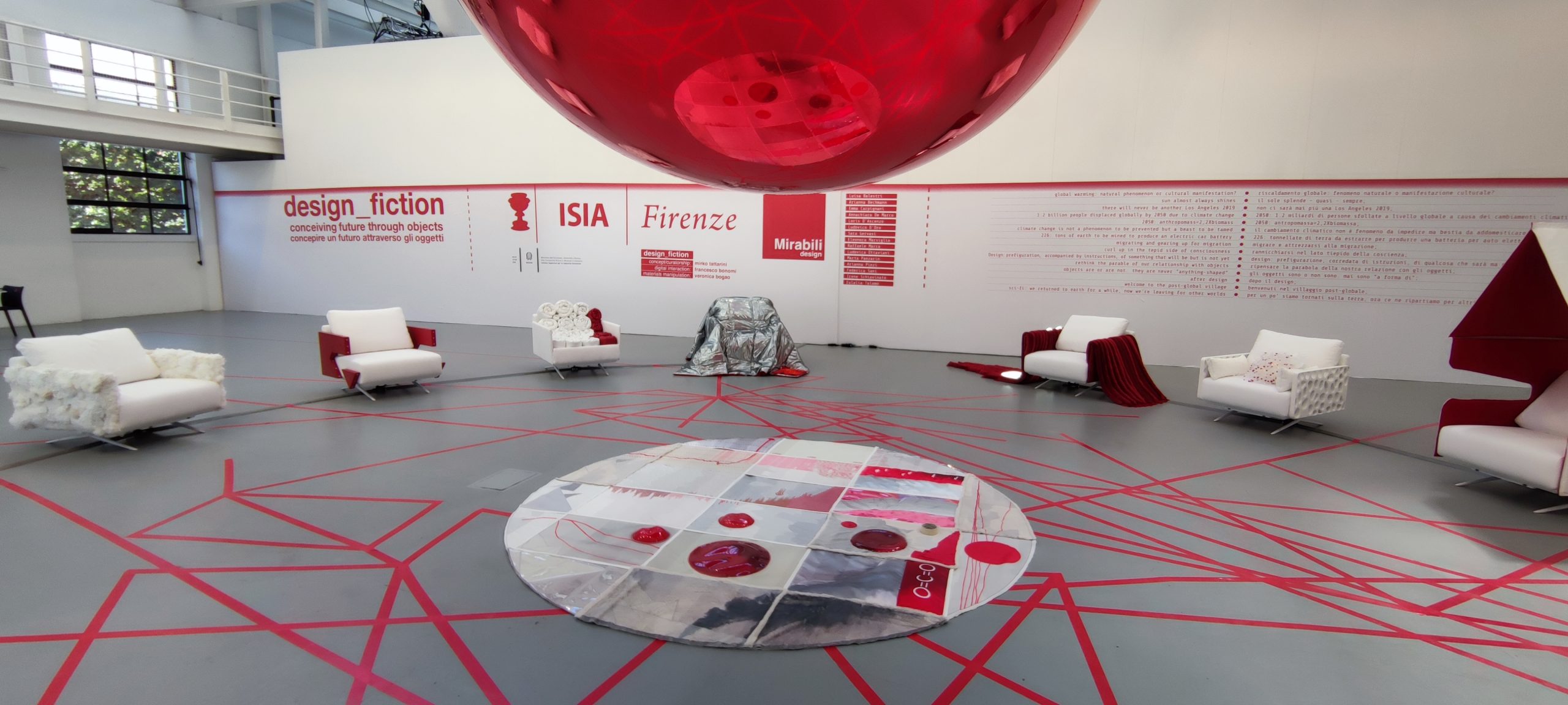 Spazio espositivo moderno a Firenze con poltrone bianche e dettagli rossi, parte di una mostra di design innovativo.