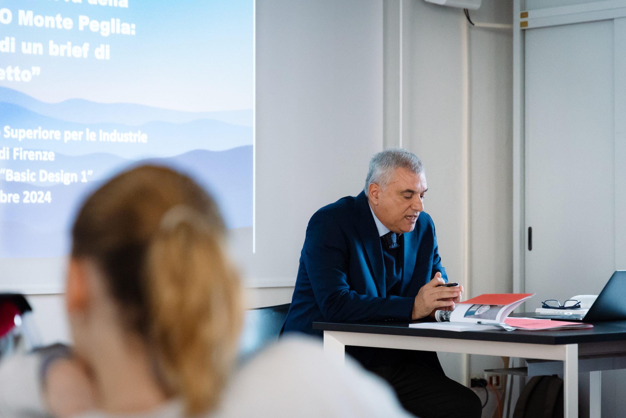 Relatore presenta argomento su Monte Peglia durante una conferenza in aula scolastica, Firenze, dicembre 2024.