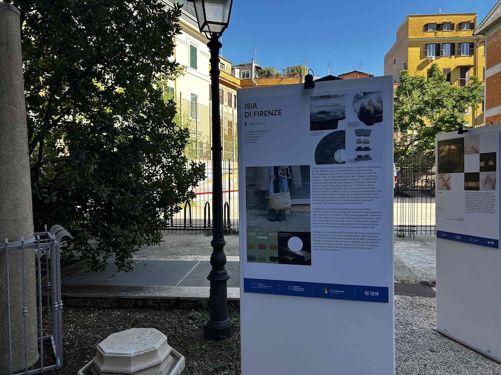 Pannello informativo ISIA di Firenze esposto in un cortile, dettagli architettonici e cielo blu sullo sfondo.