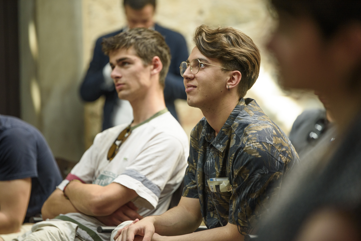 Giovani attenti durante un incontro, ascoltano con interesse una presentazione educativa in un ambiente informale.