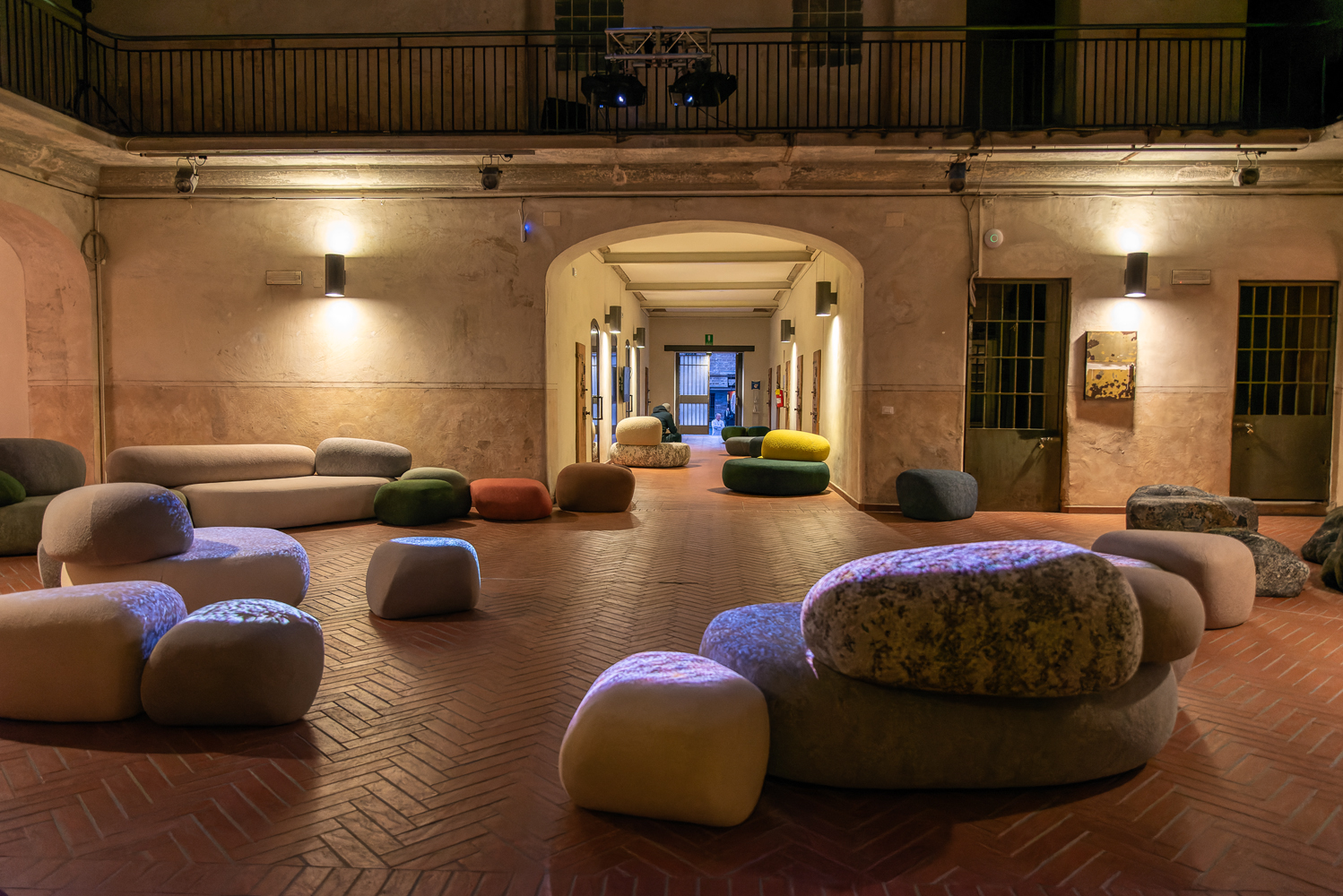 Sala d'aspetto elegante con poltroncine moderne e luminose su pavimento in cotto, illuminata da luci calde.