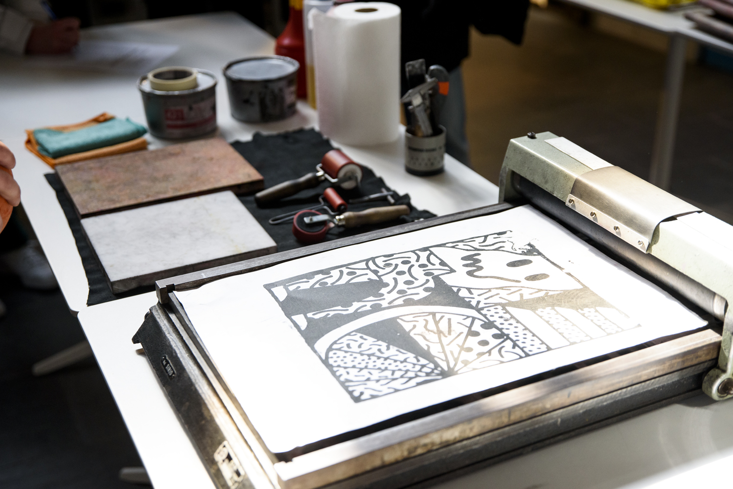 Stampa artistica in corso su un tavolo con strumenti di incisione e inchiostro.