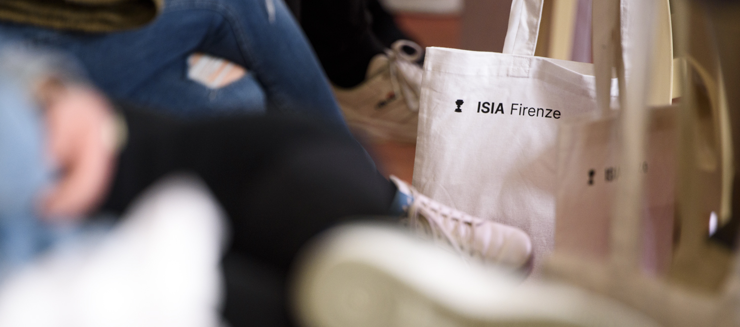 Borsa bianca con logo e scritta ISIA Firenze su fondo sfocato, simbolo di design e istruzione creativa.