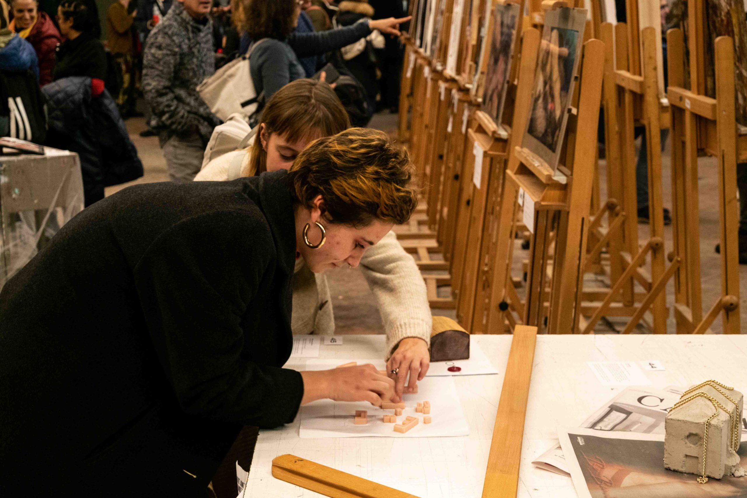 Donna coinvolta in attività artistica in galleria, con cavaletti per pittura sullo sfondo.