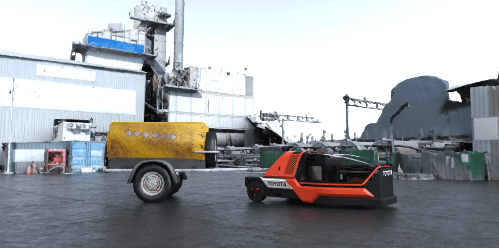 Veicolo autonomo Toyota con rimorchio giallo in un ambiente industriale abbandonato.