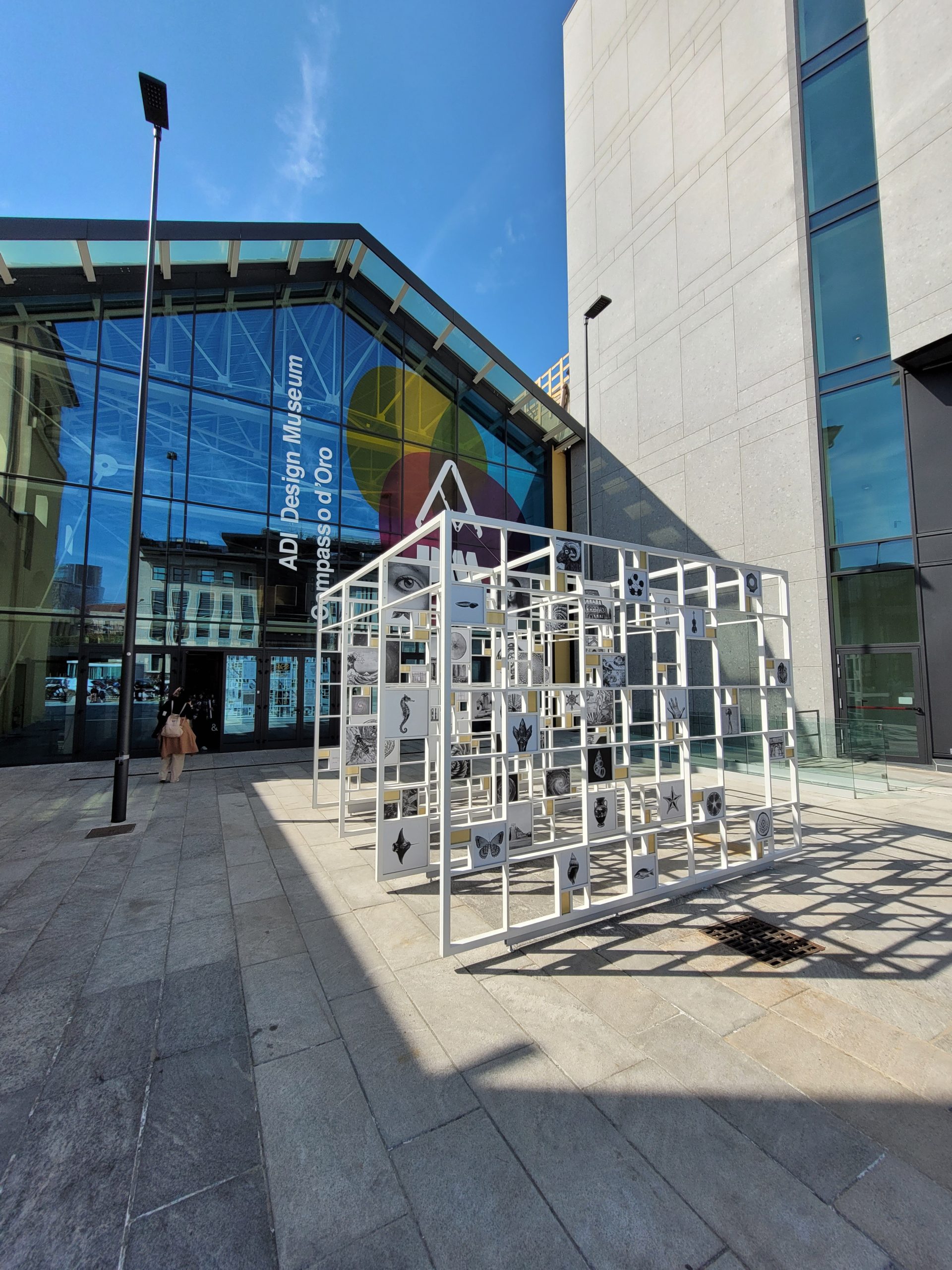 Entrata ADI Design Museum, struttura artistica e grande facciata vetrata sotto un cielo sereno.