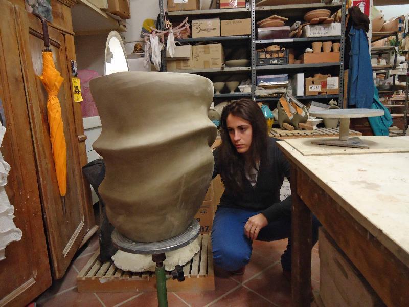 Artista concentra mentre osserva un grande vaso di argilla in uno studio di ceramica.