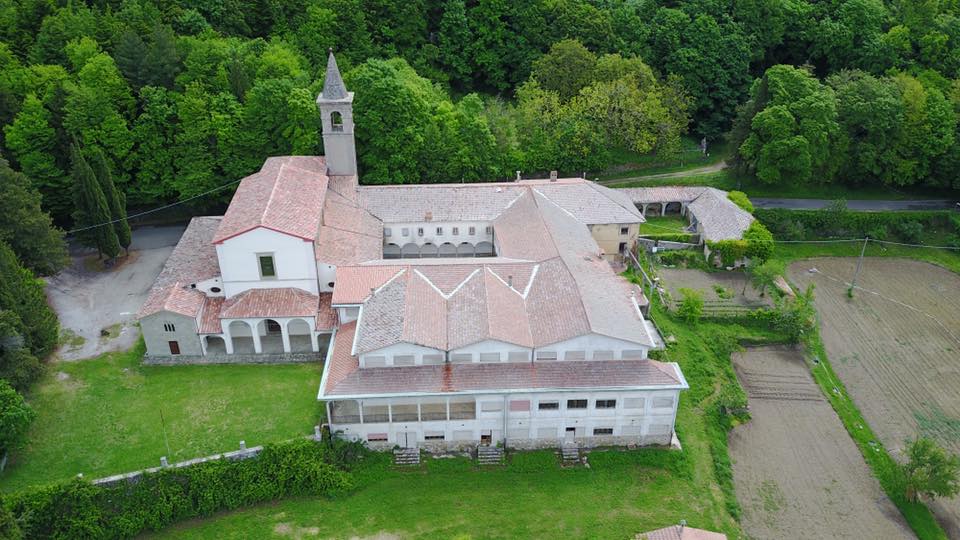 Complesso monastico storico immerso nel verde, con chiesa e torre campanaria, visto dall'alto.
