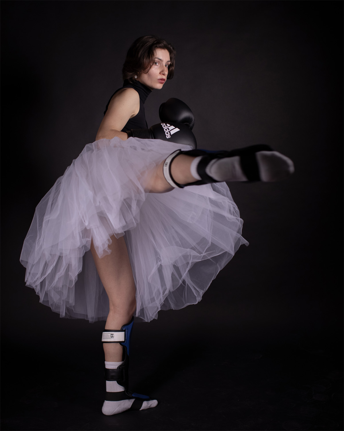 Ballerina in tutu e guantoni da boxe esegue mossa di kickboxing, unendo danza e arti marziali.