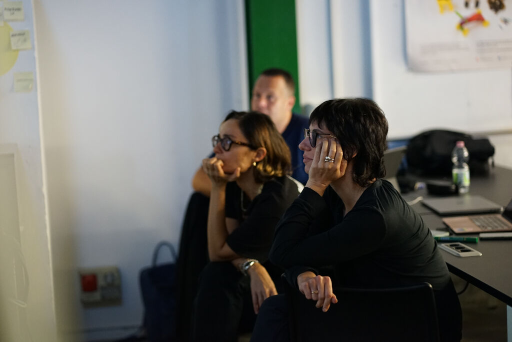 Non conosco chi siano le persone nella foto. In sala conferenze, tre persone ascoltano attentamente una presentazione.