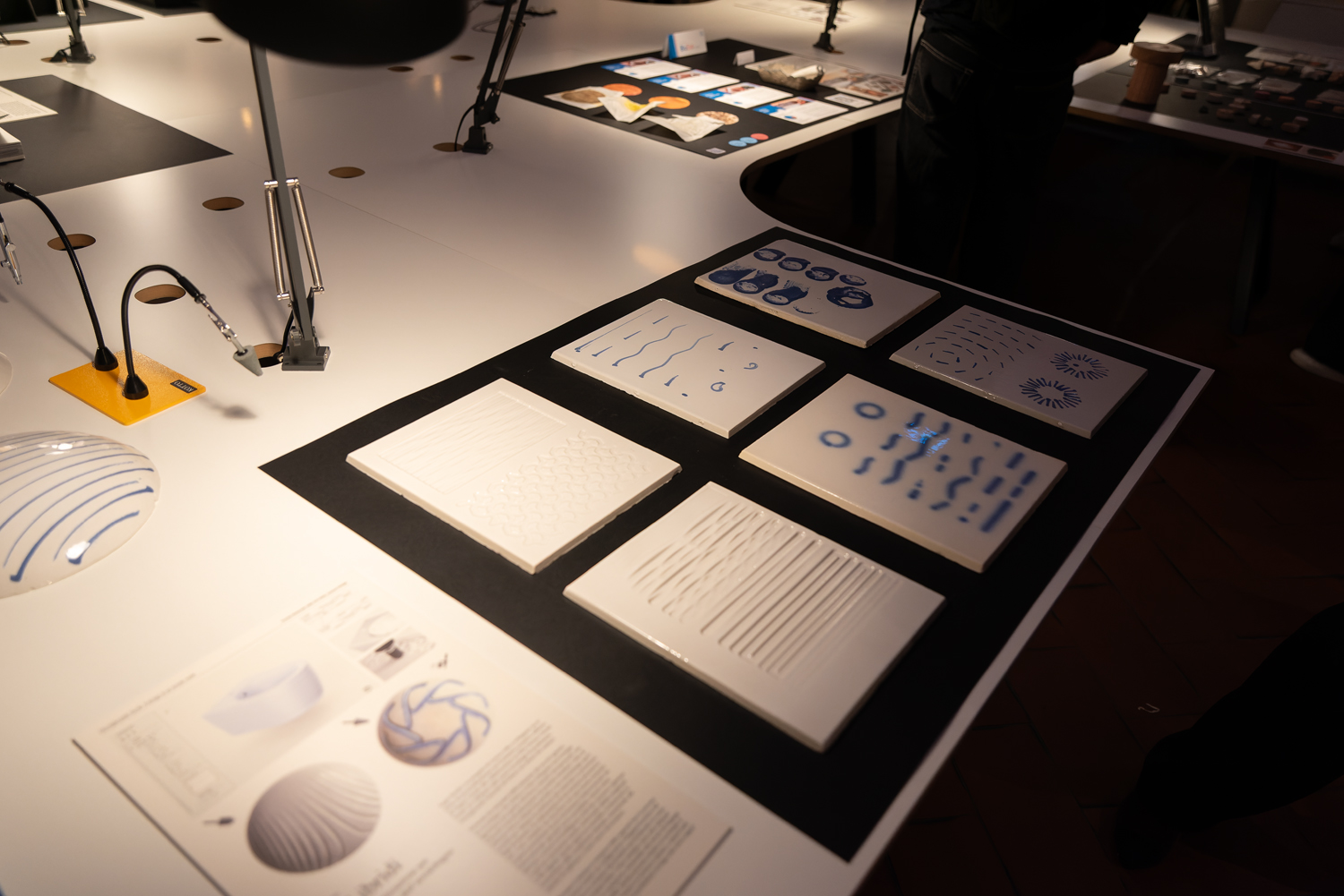 Mostra di design con piastrelle bianche e blu, dettagli su tecnologie innovative ed estetica moderna.