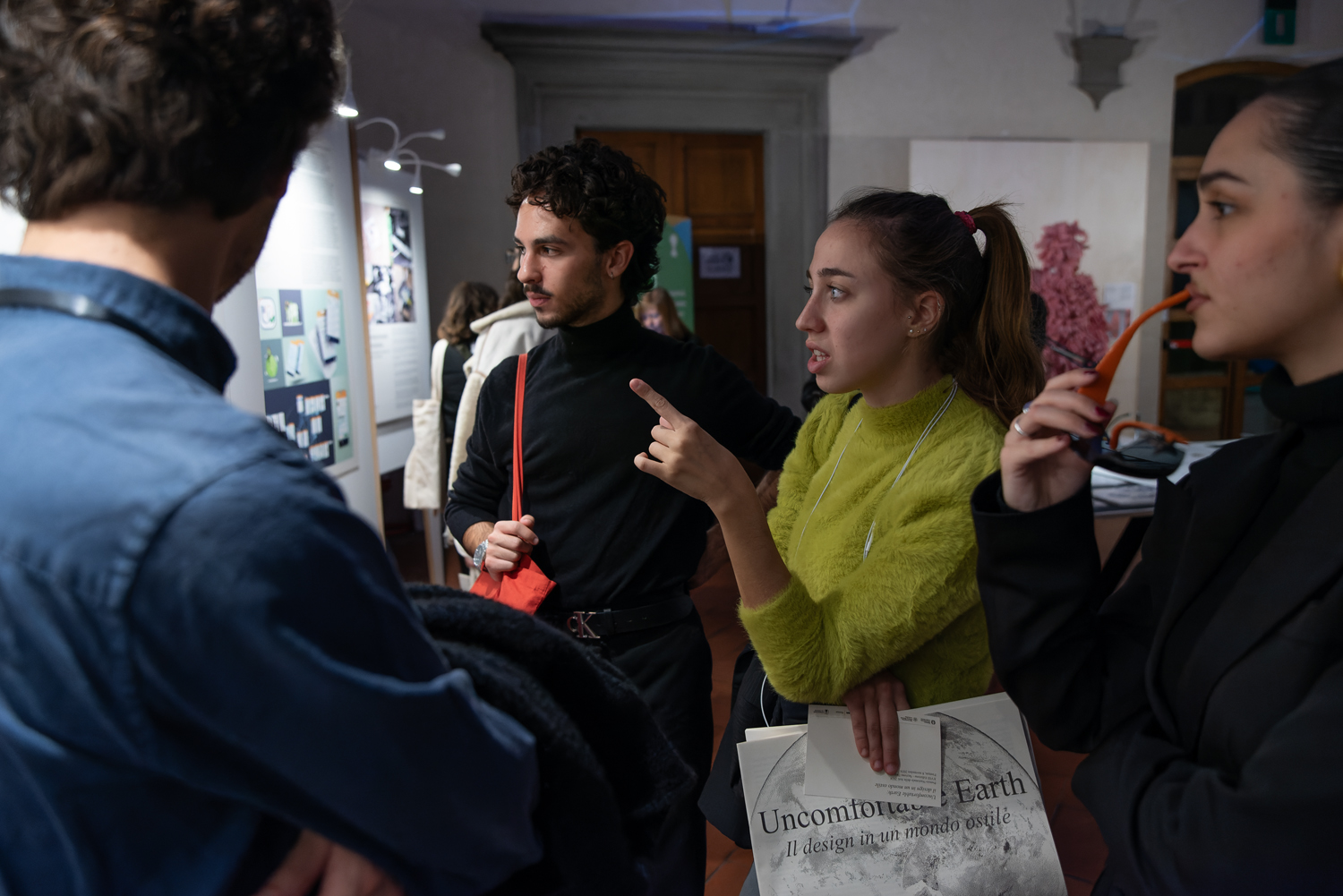 Persone discutono appassionatamente davanti a una mostra d'arte moderna, evidenziando dettagli su un pannello.