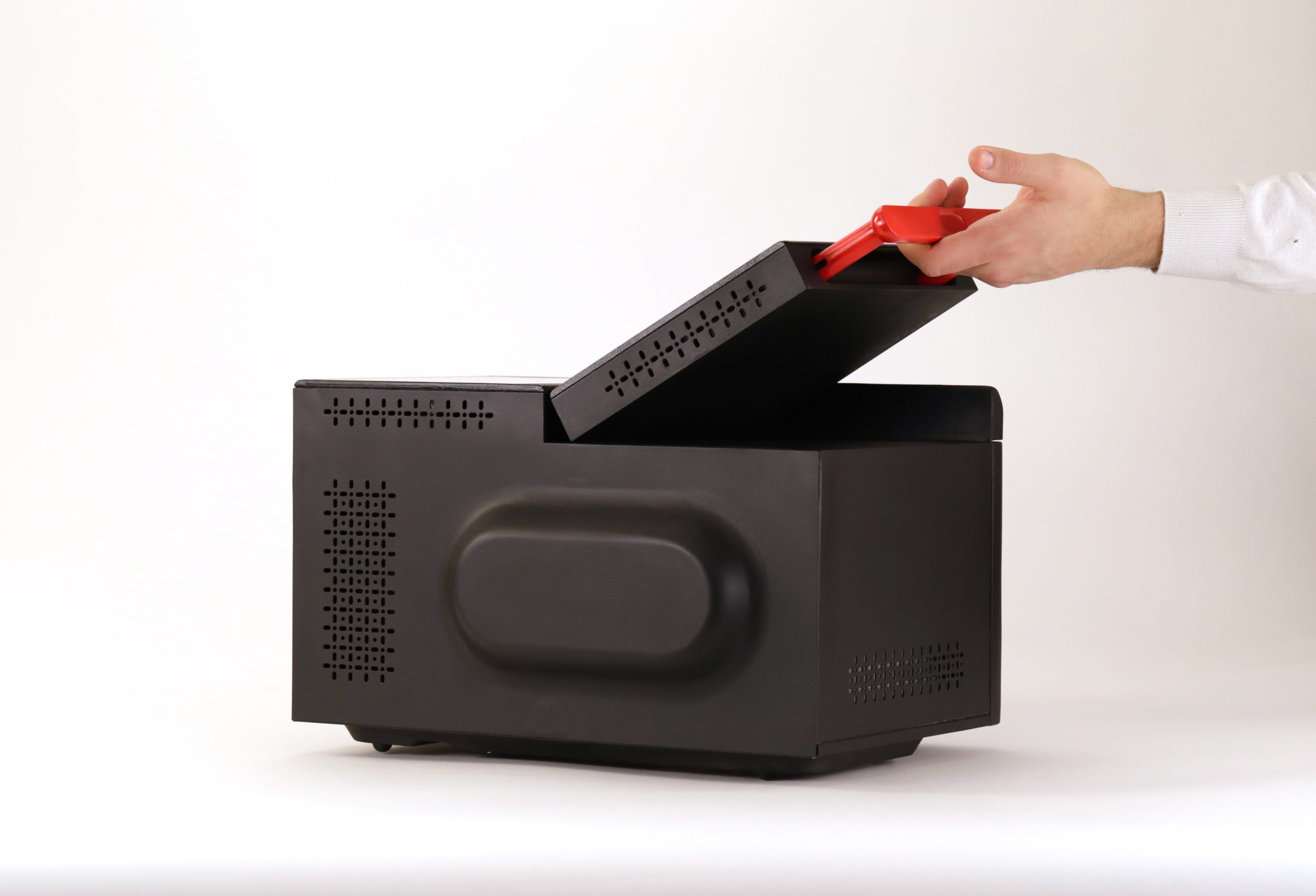 Mano apre la cassa nera con coperchio rosso, design moderno.