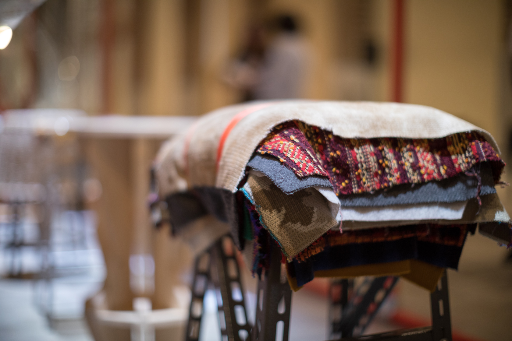 Pezzetti di tessuto colorato impilati su un tavolo in un ambiente interno sfocato.