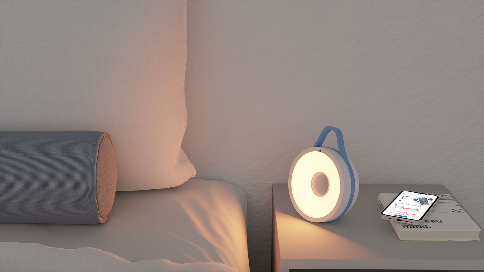 Lampada da comodino moderna accesa accanto a un cuscino cilindrico e un telefono su un libro.
