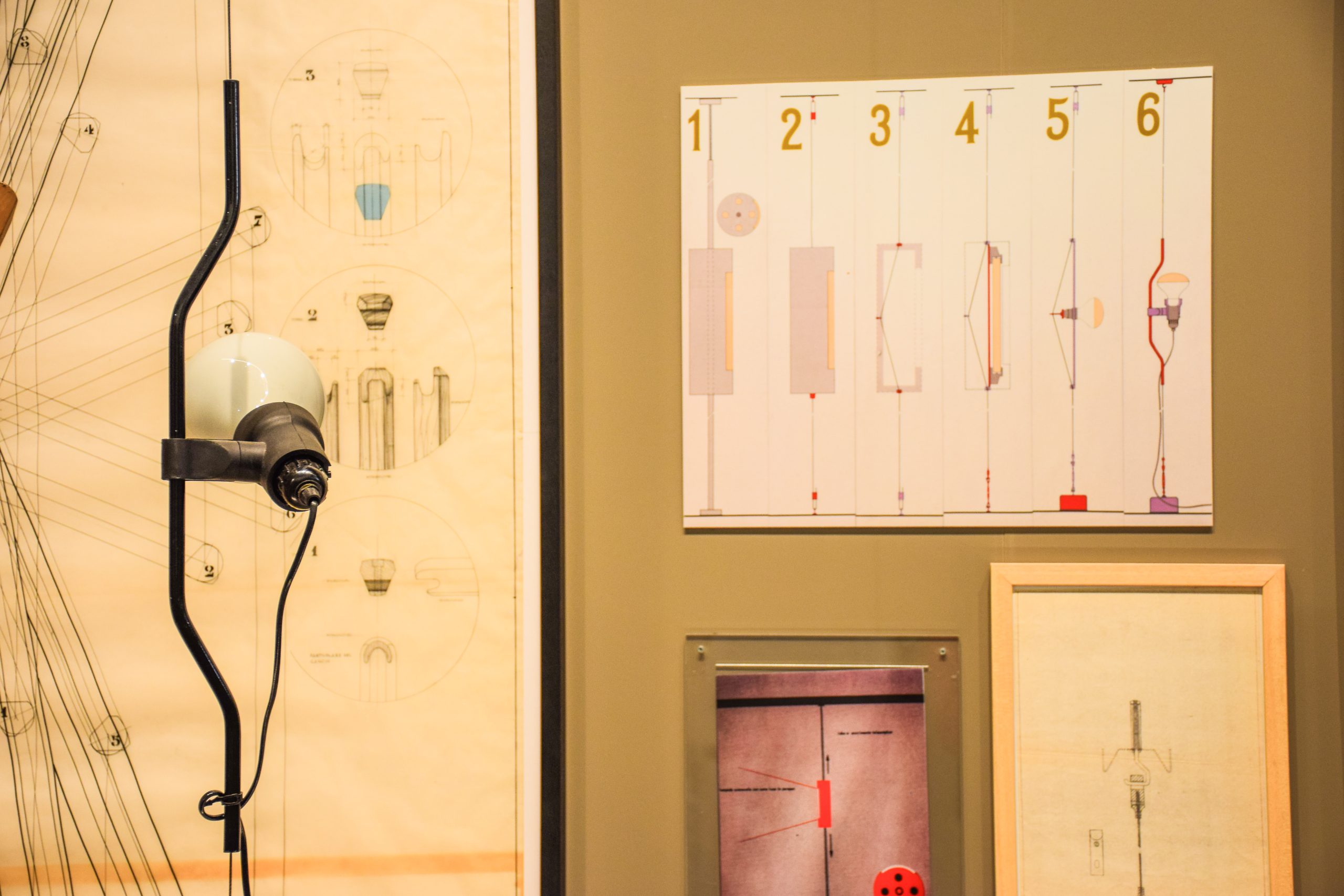 Disegni tecnici e illustrazioni da esposizione di design con lampada, poster numerati e progetto dettagliato.
