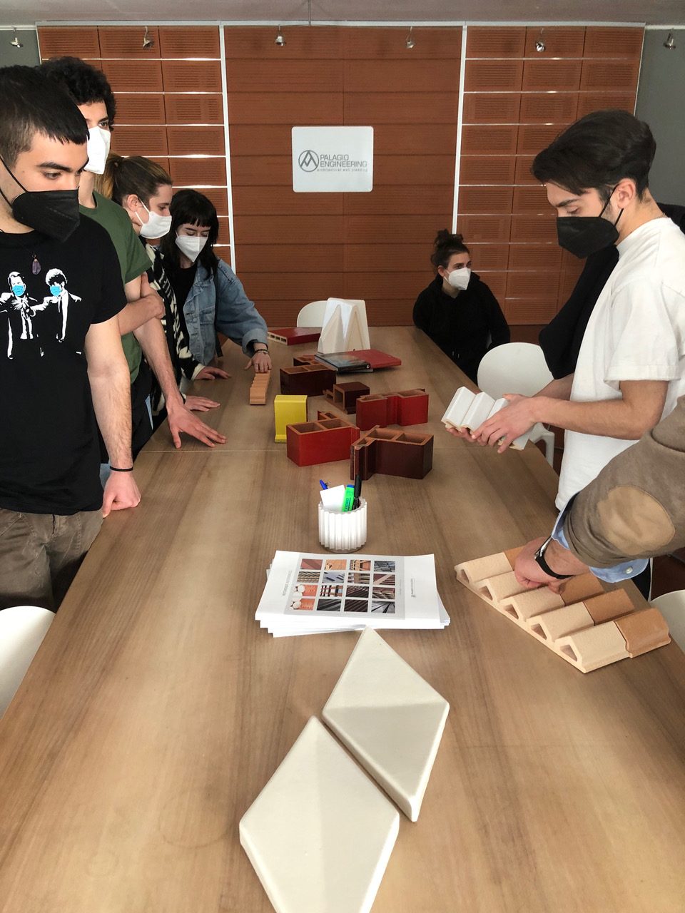Giovani studenti discutono intorno a un tavolo modelli architettonici, progettazione innovativa.