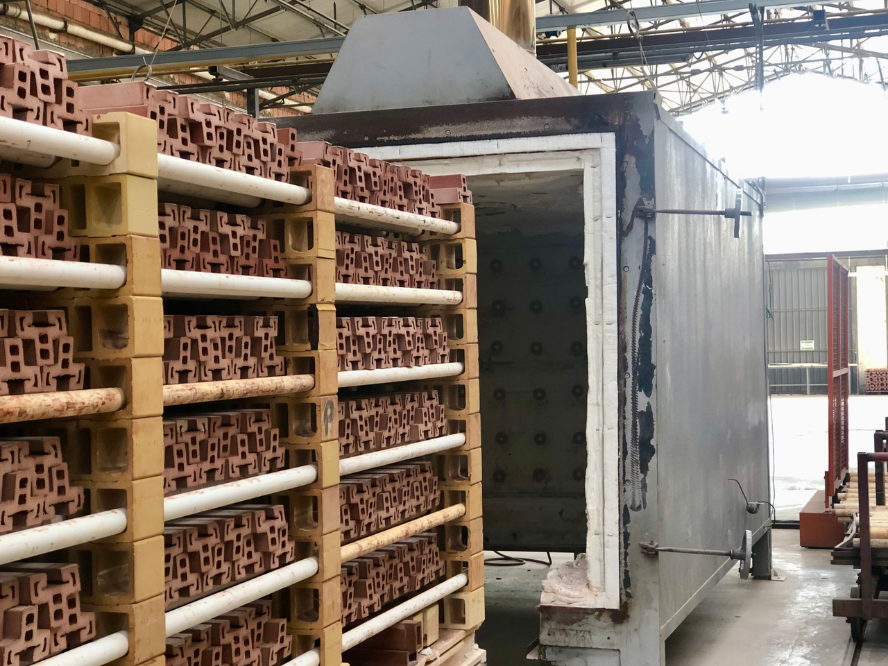Forno industriale con mattoni pronti per la cottura in un impianto di produzione, ambiente di fabbrica.
