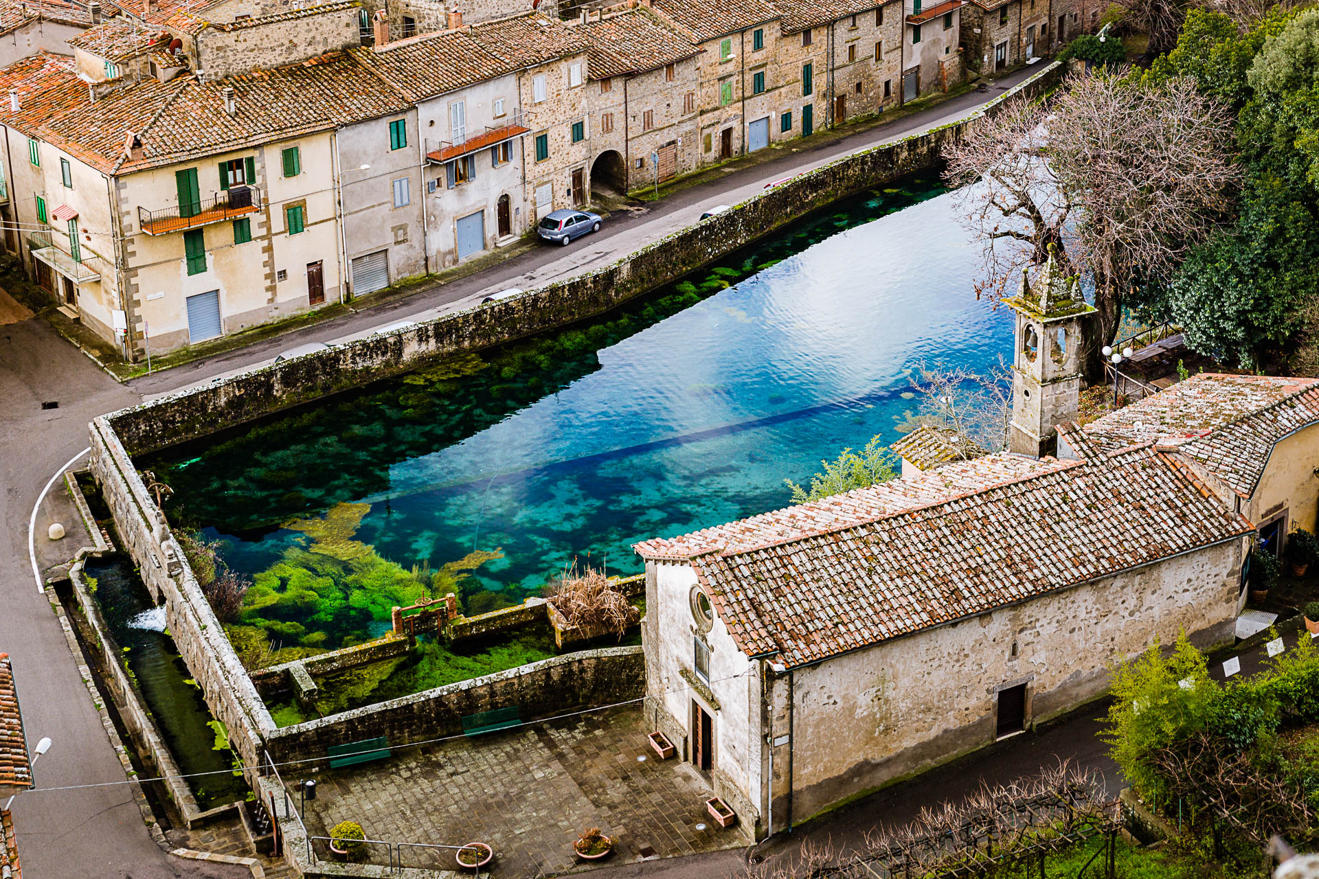 Antico borgo italiano con case in pietra e corso d'acqua cristallino, atmosfera storica e pittoresca.