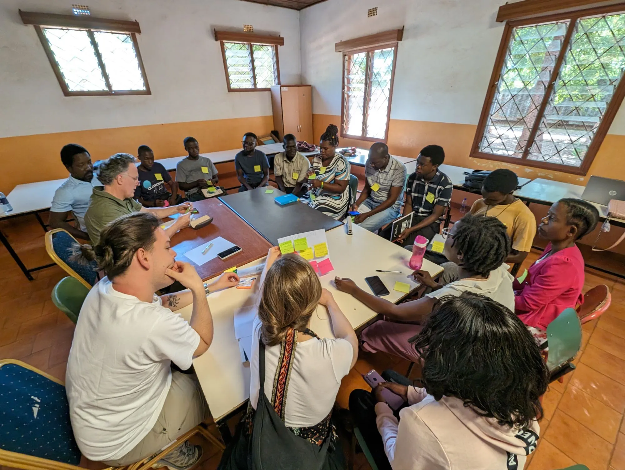 Un gruppo di persone riunite attorno a un tavolo discutono e condividono idee in una sala luminosa.
