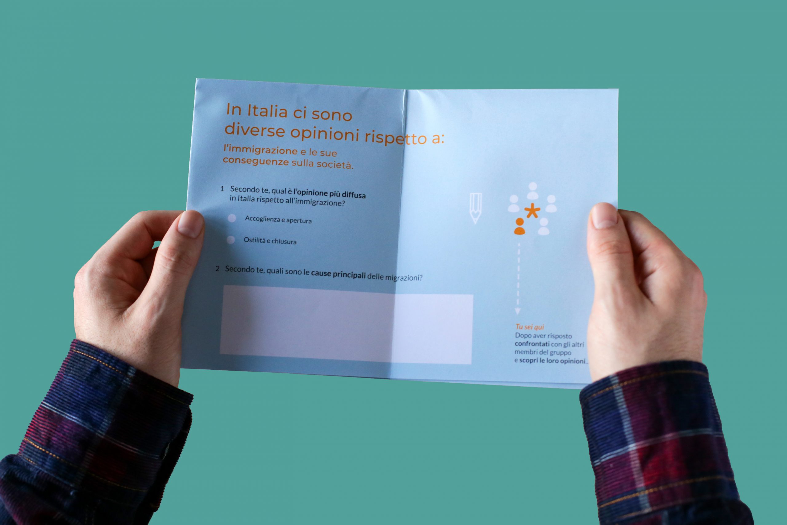 Due mani tengono un volantino con domande sull'opinione pubblica italiana riguardo l'immigrazione e le sue cause.
