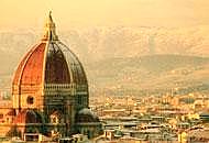 Cupola del Duomo di Firenze al tramonto, con montagne visibili sullo sfondo. Panorama suggestivo e storico.